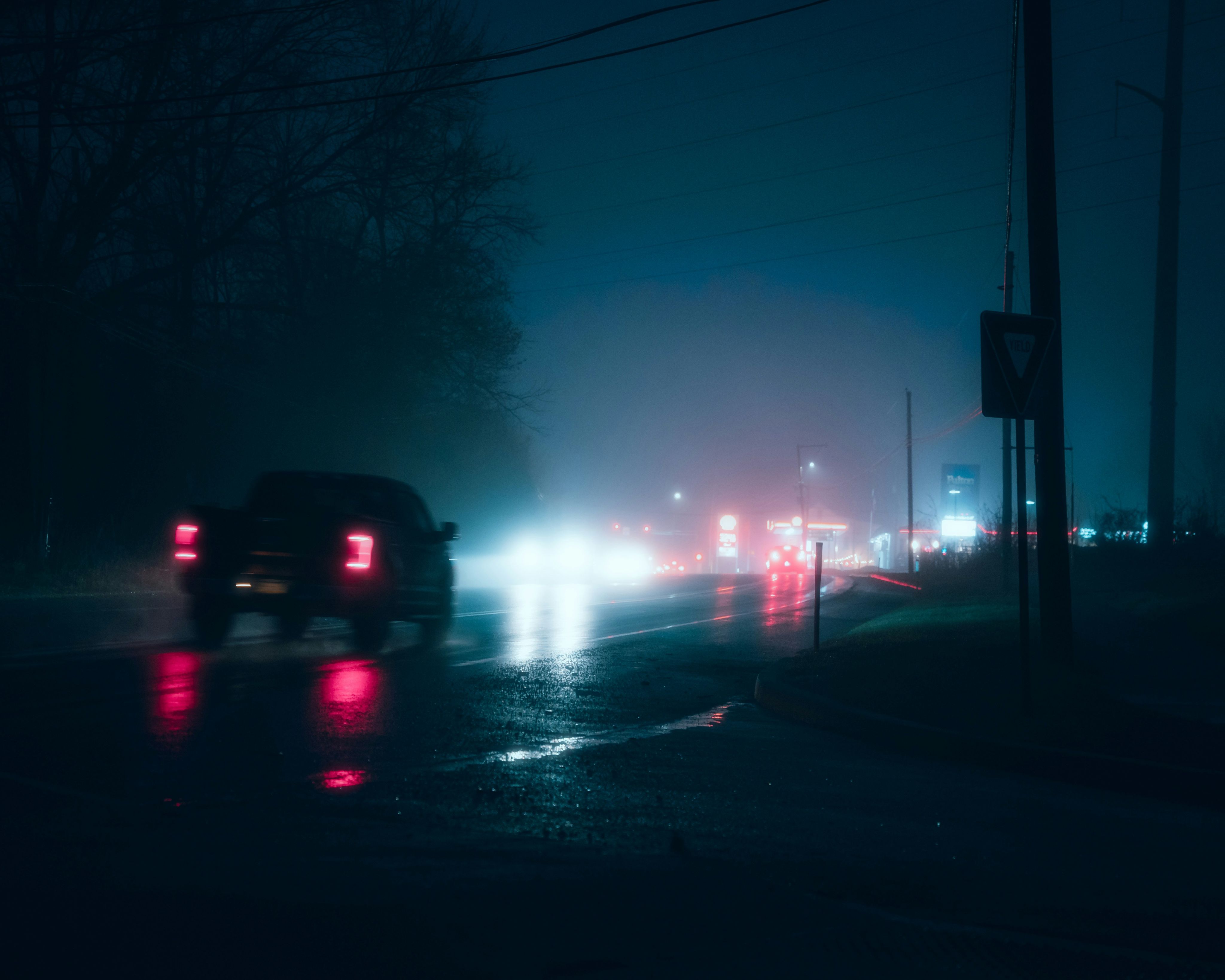 Cars driving on a wet road at night.