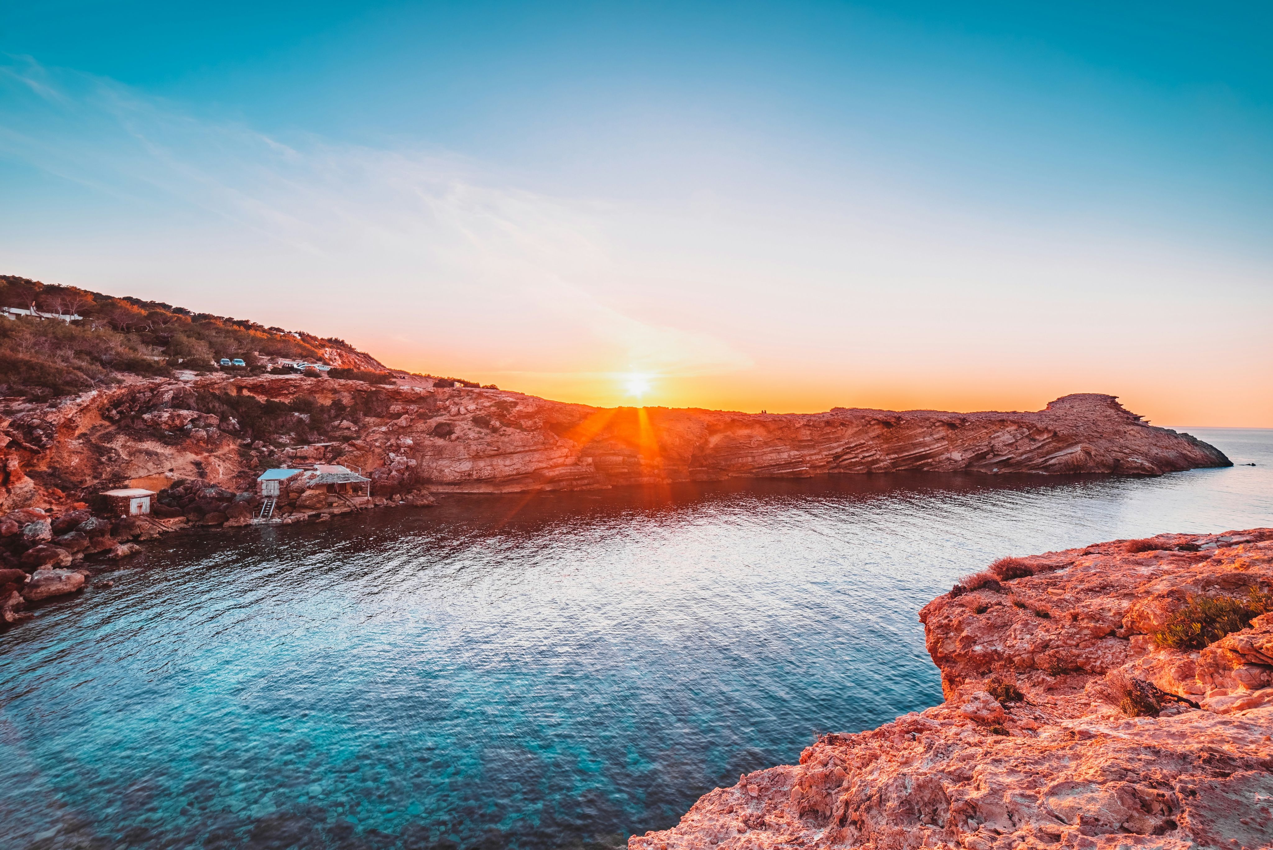 brown rocky mountain beside body of water during sunset