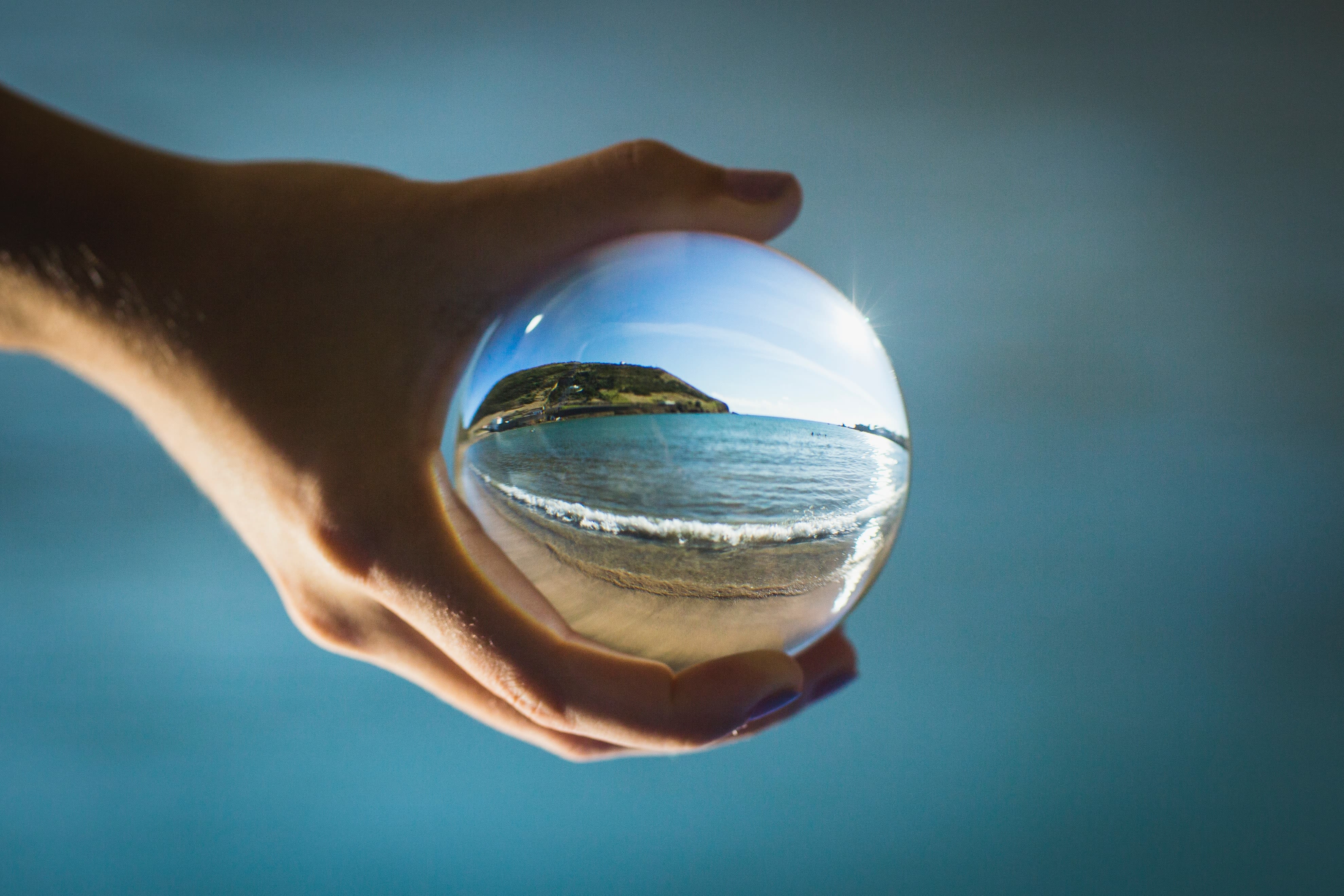 Mano sosteniendo una esfera transparente que muestra el planeta Tierra, representando el impacto global de los hábitos individuales.