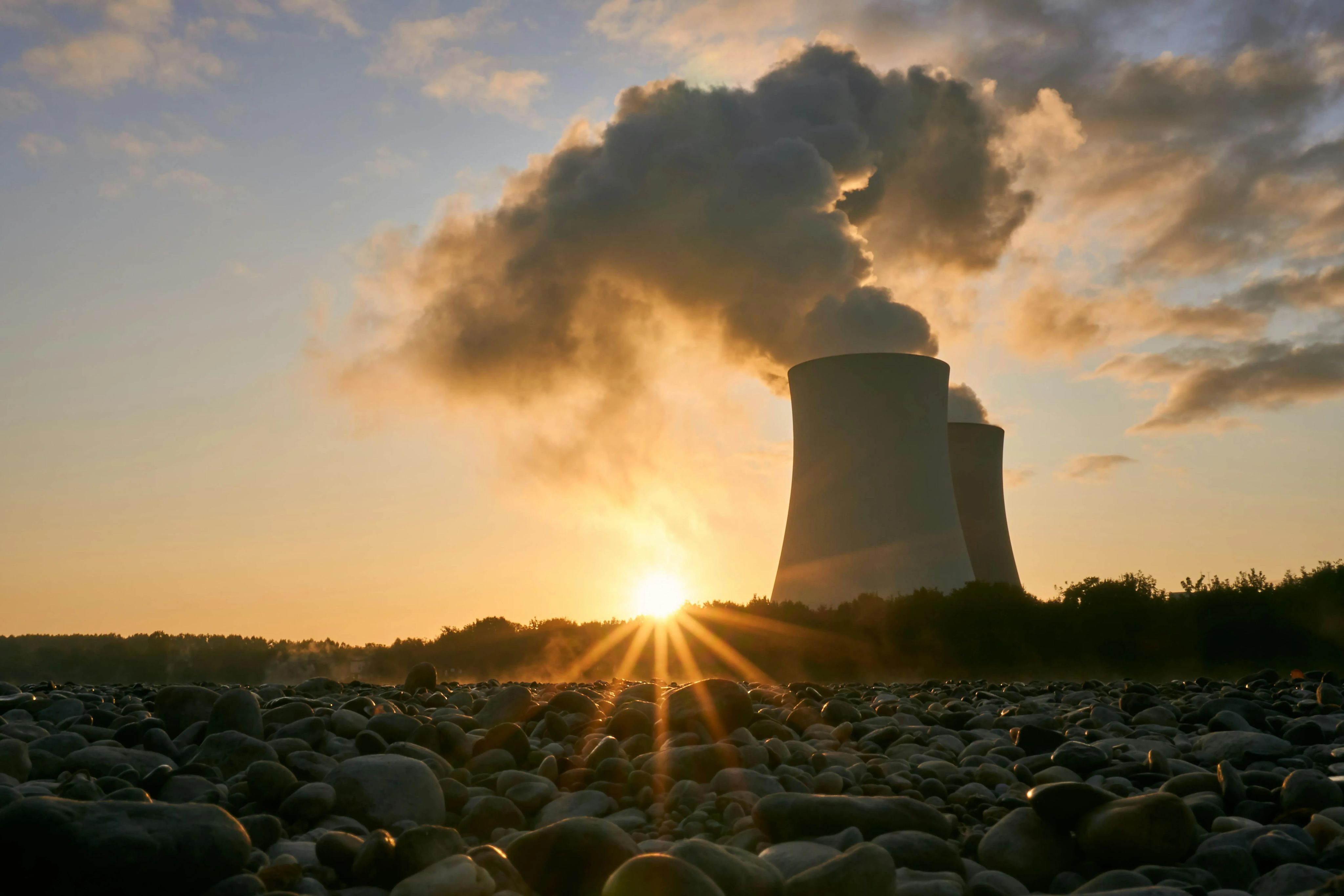 Plantas de energía nuclear emitiendo vapor con el Sol de fondo